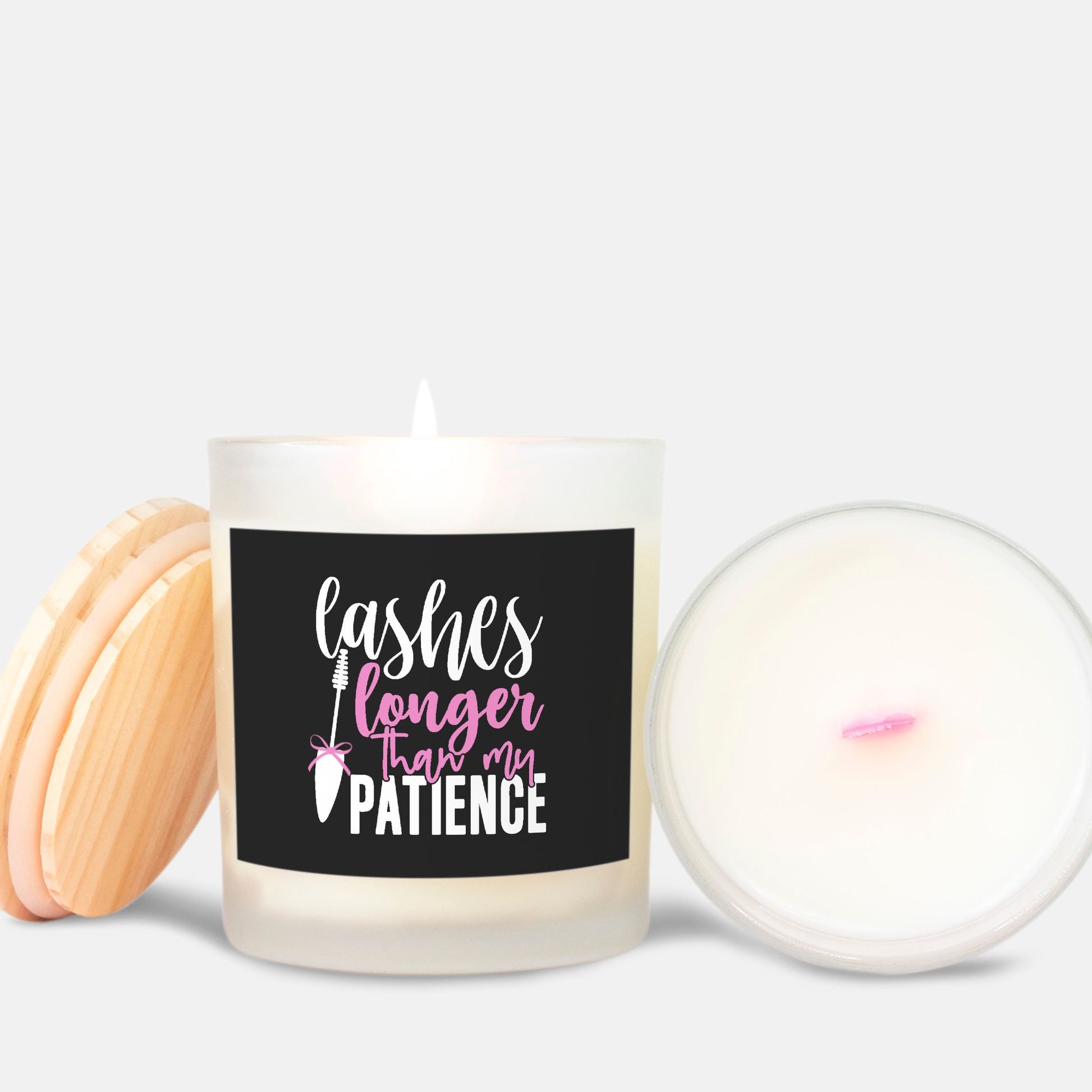 Lashes longer than my patience funny quote on a white soy candle. Wood lid on a frosted glass with a pink wick candle. Black, white and pink with a mascara brush with a pink bow.